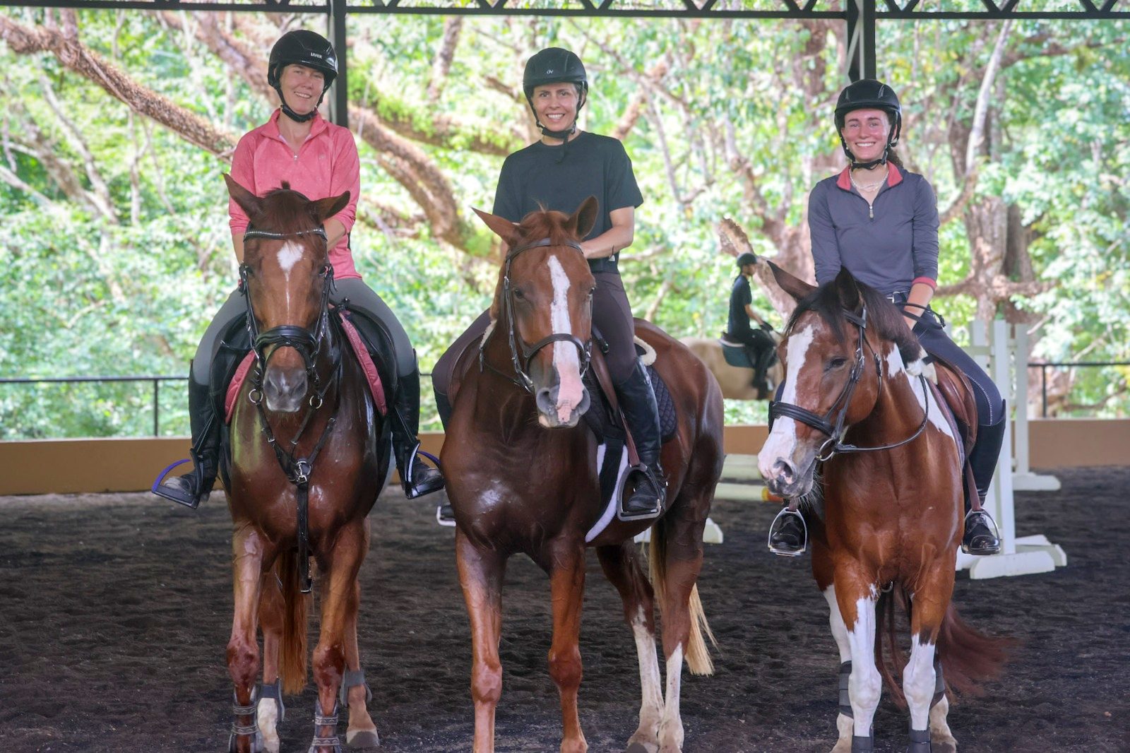 Three riders on horseback in the arena